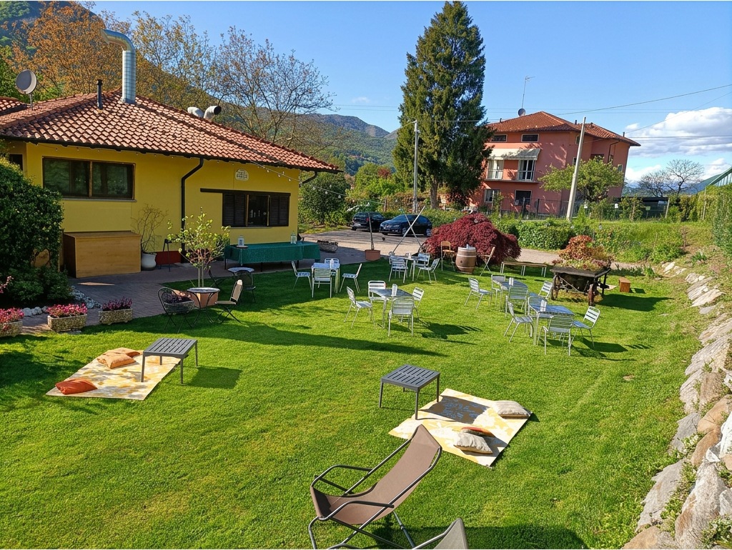 Il giardino visto dall'alto con tavolini e angolo picnic accanto alla casa